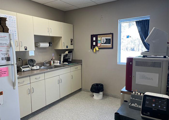 A medical office with cabinets, a sink, equipment, and a window showing snow outside.