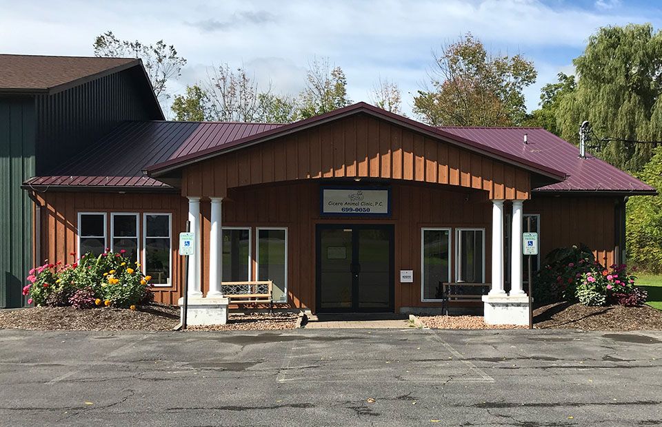Small medical clinic with red roof and wooden siding, surrounded by colorful flowers.