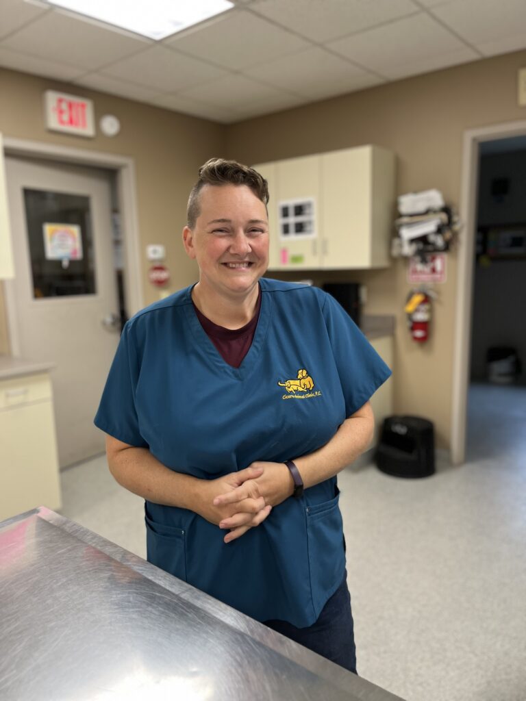 Smiling person in teal scrubs standing in a clinic.